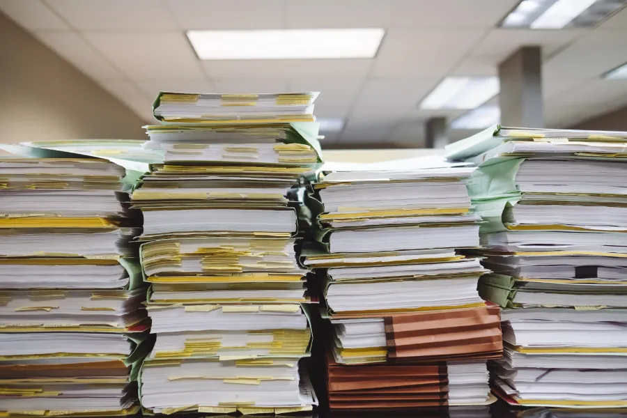 Muchos documentos jurídicos, con notas en sus hojas, amontonados sobre una mesa de oficina