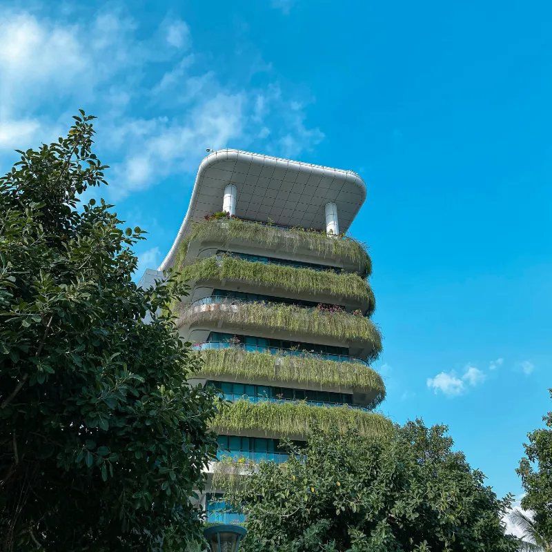 Vista de un edificio sostenible de sinuosas formas con plantas en todos sus balcones. 