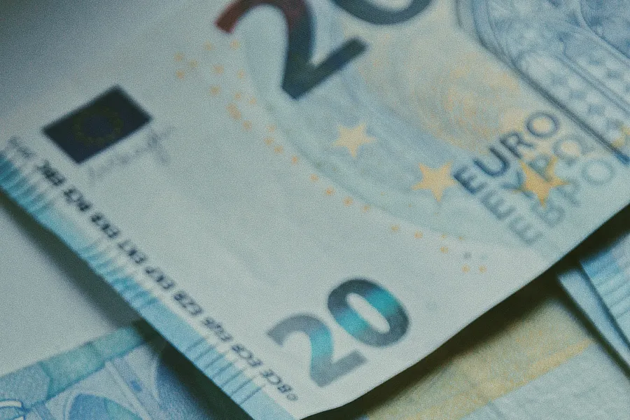 Primer plano de un billete de 20 euros, mostrando detalles nítidos como las estrellas amarillas y el texto "EURO" en la esquina superior derecha. La imagen destaca el billete de euro con colores vivos, simbolizando el tema financiero y el impacto del euríbor en las hipotecas variables.