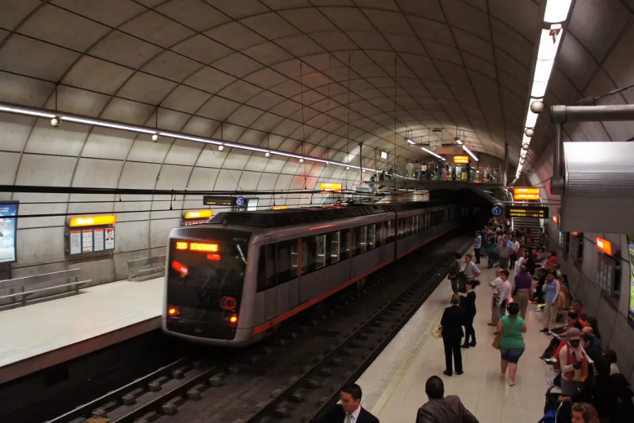 Una estación del metro de Bilbao con gente en donde se ve que un metro está haciendo una parada.