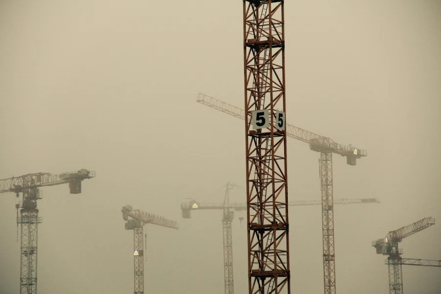 Vista de un grupo de seis grúas de la construcción sumidas en una niebla blanquecina espesa