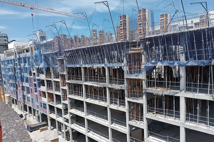 Edificio en construcción de Tu Casa en Amézola, con estructura de concreto visible y redes de seguridad en el nivel superior. Se observa una grúa y un cielo despejado de fondo. El proyecto muestra el progreso y desarrollo de la nueva vivienda.