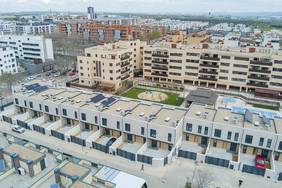 Vista aérea de la promoción de Trinosa Soto II, recientemente entregada a los propietarios. Se destacan las casas adosadas modernas de la promoción Soto II en la mitad inferior de la imagen y edificios residenciales con áreas comunes bien cuidadas en la parte superior.